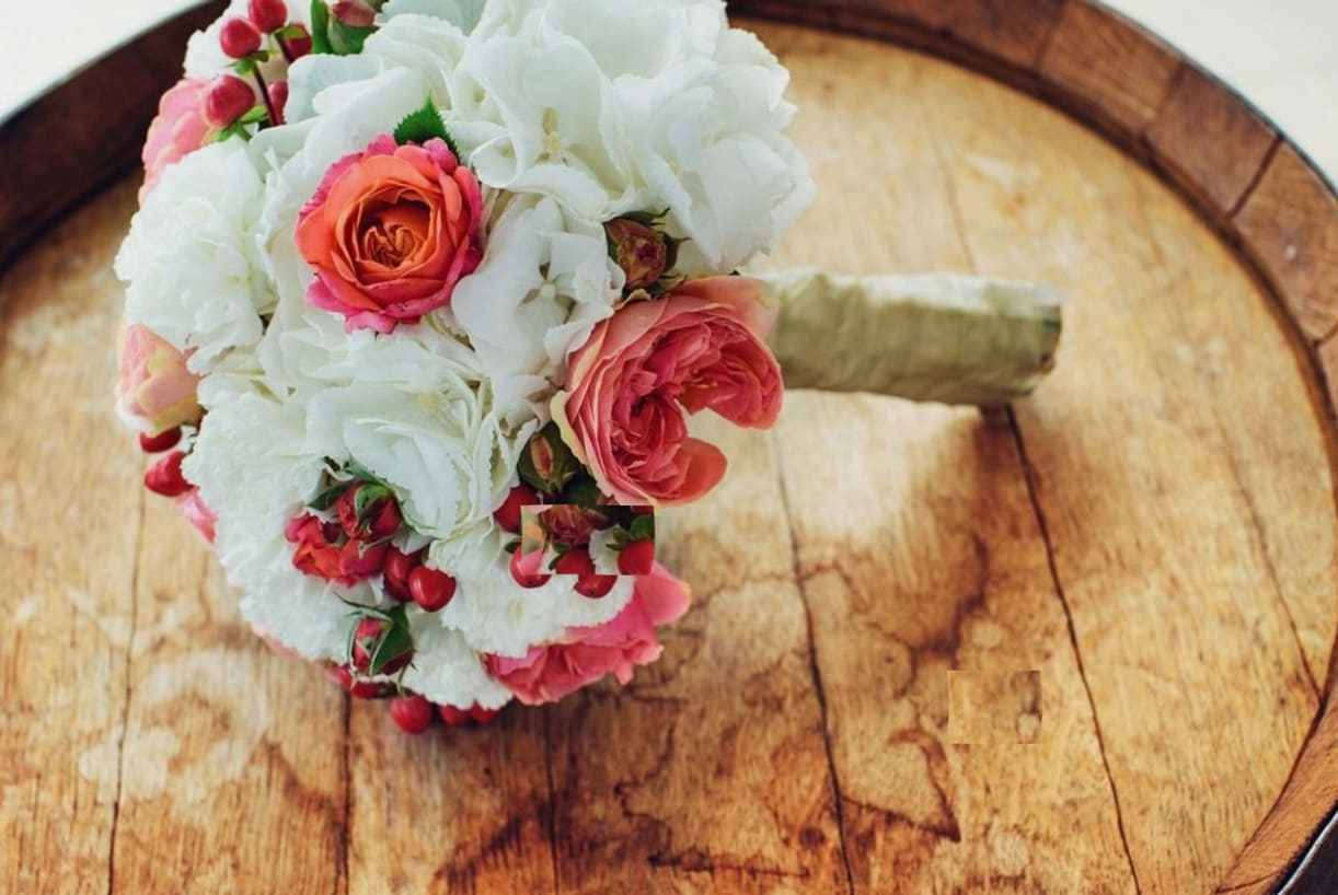 Brautstrauß aus Hortensien und Rosen auf einem Holzfass